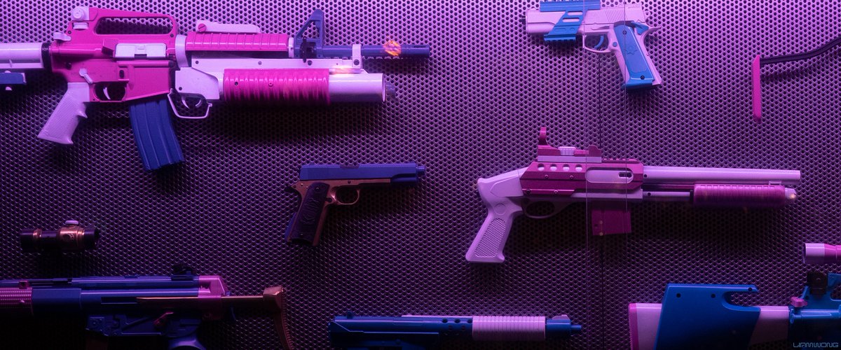 Photography by Liam Wong of Seoul at night. Plastic replica guns inside a vending machine. They're colored pink and purple in plastic.