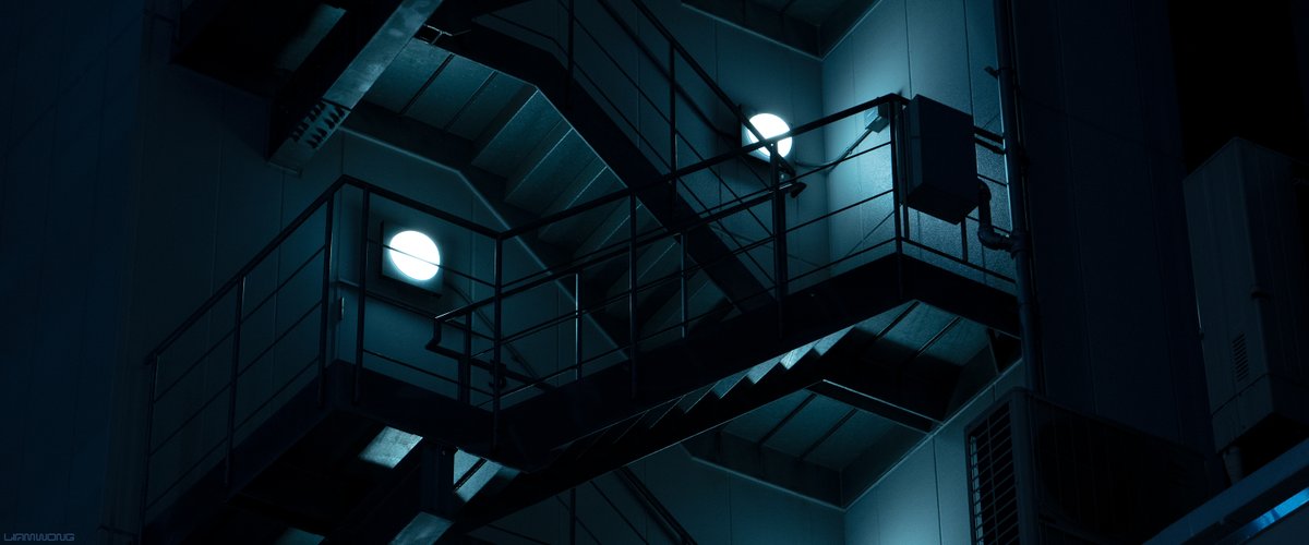 Photography by Liam Wong of Tokyo at night - focusing on simple shapes and color in architecture. This image is of a set of fire exit stairs high up in a modern building. It is a desaturated blue color.