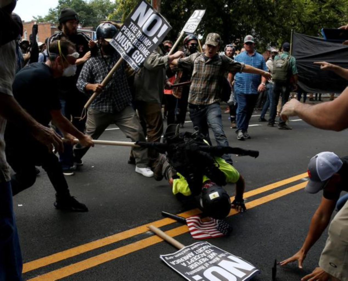 Charlottesville.Heavyset older man in the the dark-blue-lighter-blue checked shirt and tan baseball cap.In the background.