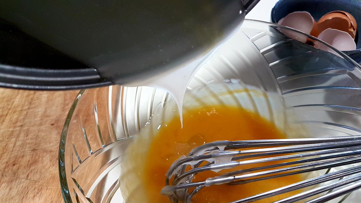 Slowly stir at least half of the hot mixture into the eggs yolks, whisking evenly all the time. (A second pair of hands is very helpful for this step.)