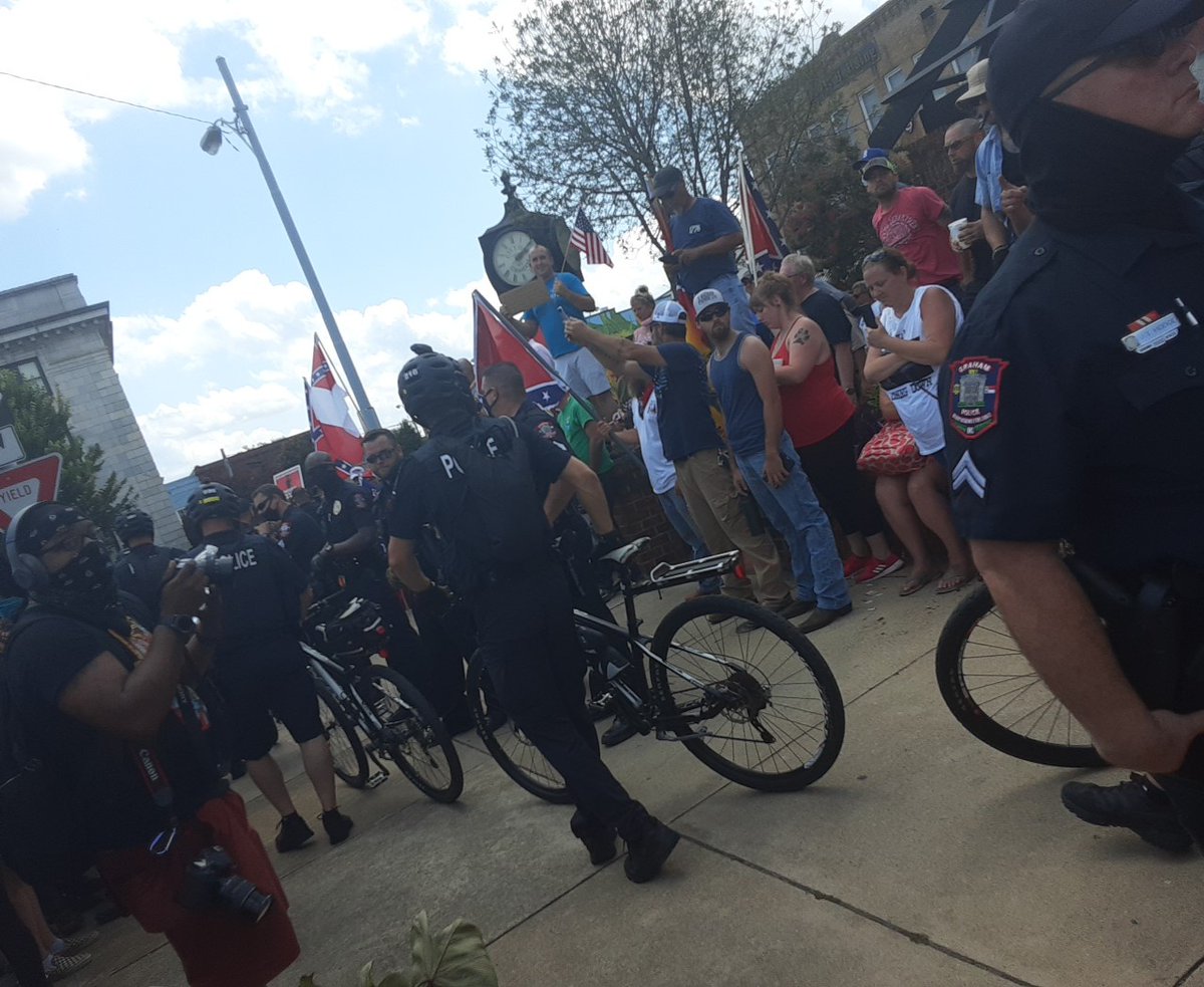 Cops try to push anti-racists off sidewalk. Charlotte bike cops moving in.