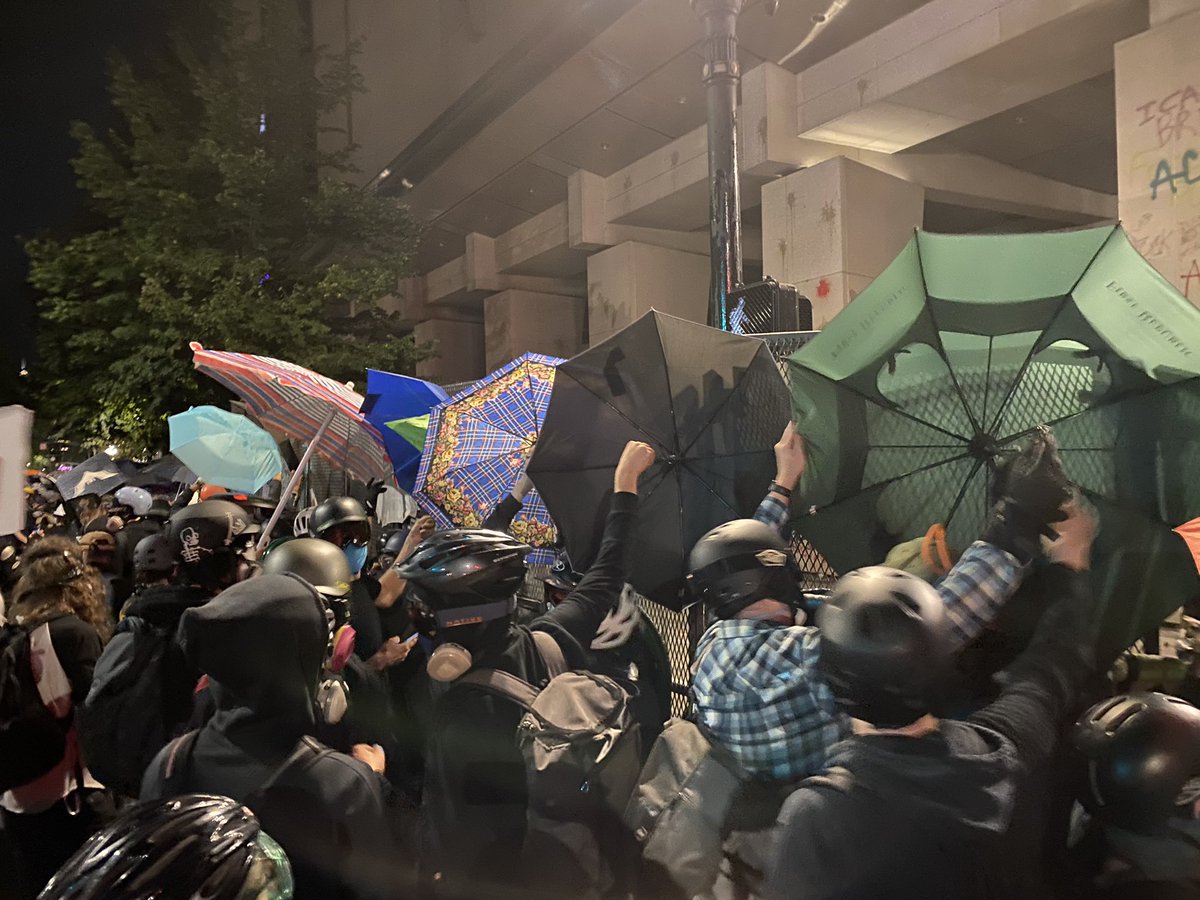 Frontline protesters covering fence with umbrellas to protect from Feds firing pepper spray balls  #PortlandProtests