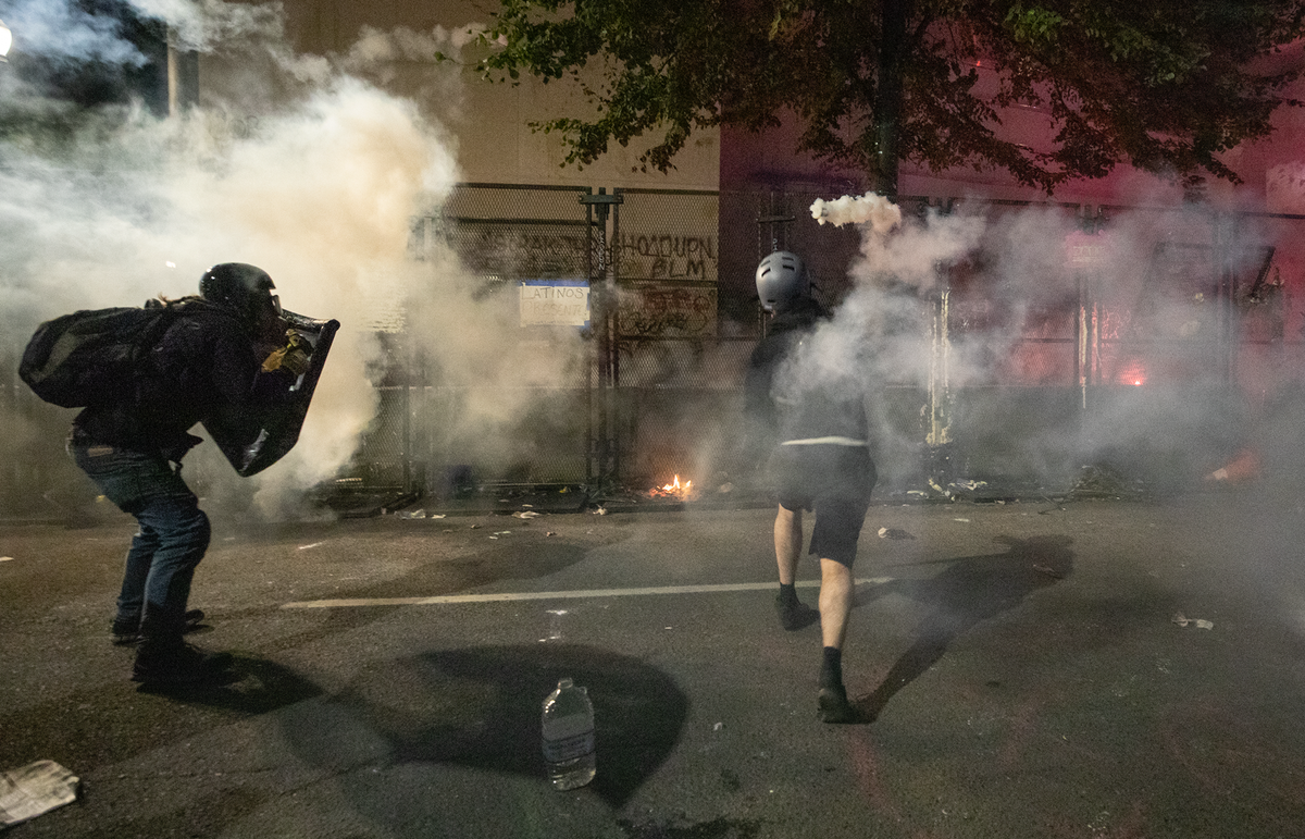 Events picked up as protesters banged and shook the fence. Tear gas canisters were thrown over and back again. Protesters used laser pointers on a spotter that was positioned high up.