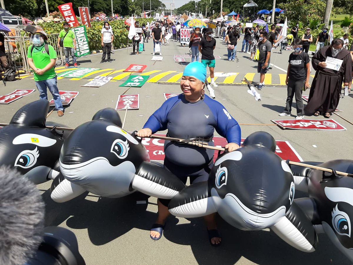 ABSCBNNews's tweet photo. Matapos mag-ala Debold Sinas sa "Grand Mañanita" protest sa UP Diliman noong Hunyo 12, tila ginaya naman ng aktibistang si Juana Change ang litrato ni Pres'l spokesman Harry Roque kasama ang ilang dolphins sa Subic sa #SONA2020 rally ngayong Lunes. | Davinci Maru, ABS-CBN News https://t.co/8MSDEj8bdD