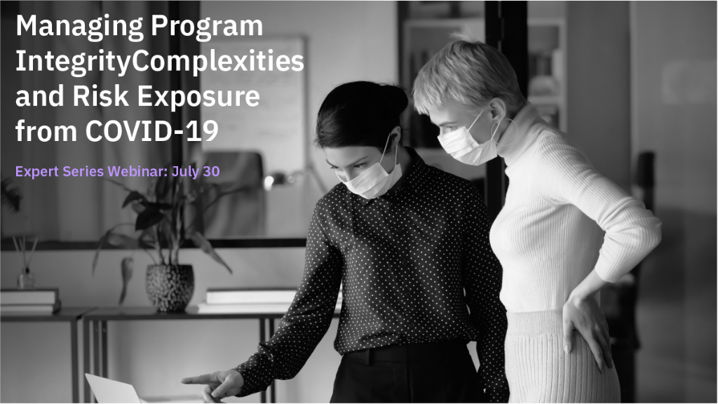 Two masked women looking at computer.