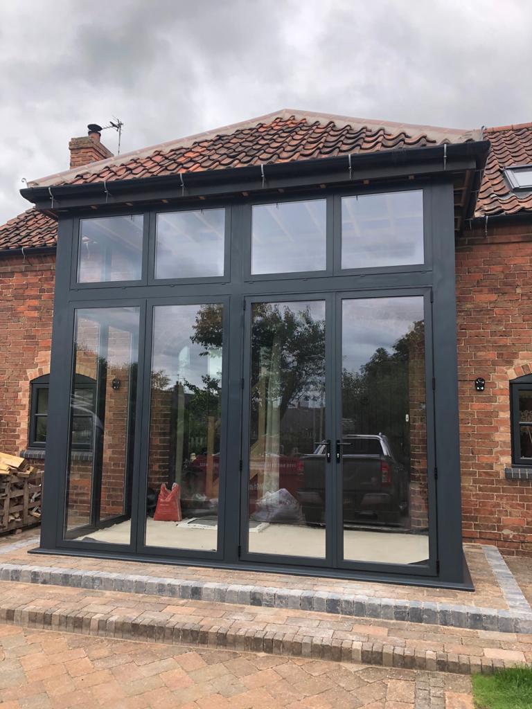 Grey aluminium porch with dummy sashes including highly impressive 2500mm high french door as apposed to your average 2100mm. Installed in Edwalton, Nottingham. For a free quotation call us on 01158 660066, visit thenottinghamwindowcompany.co.uk or pop into our West Bridgford showroom.