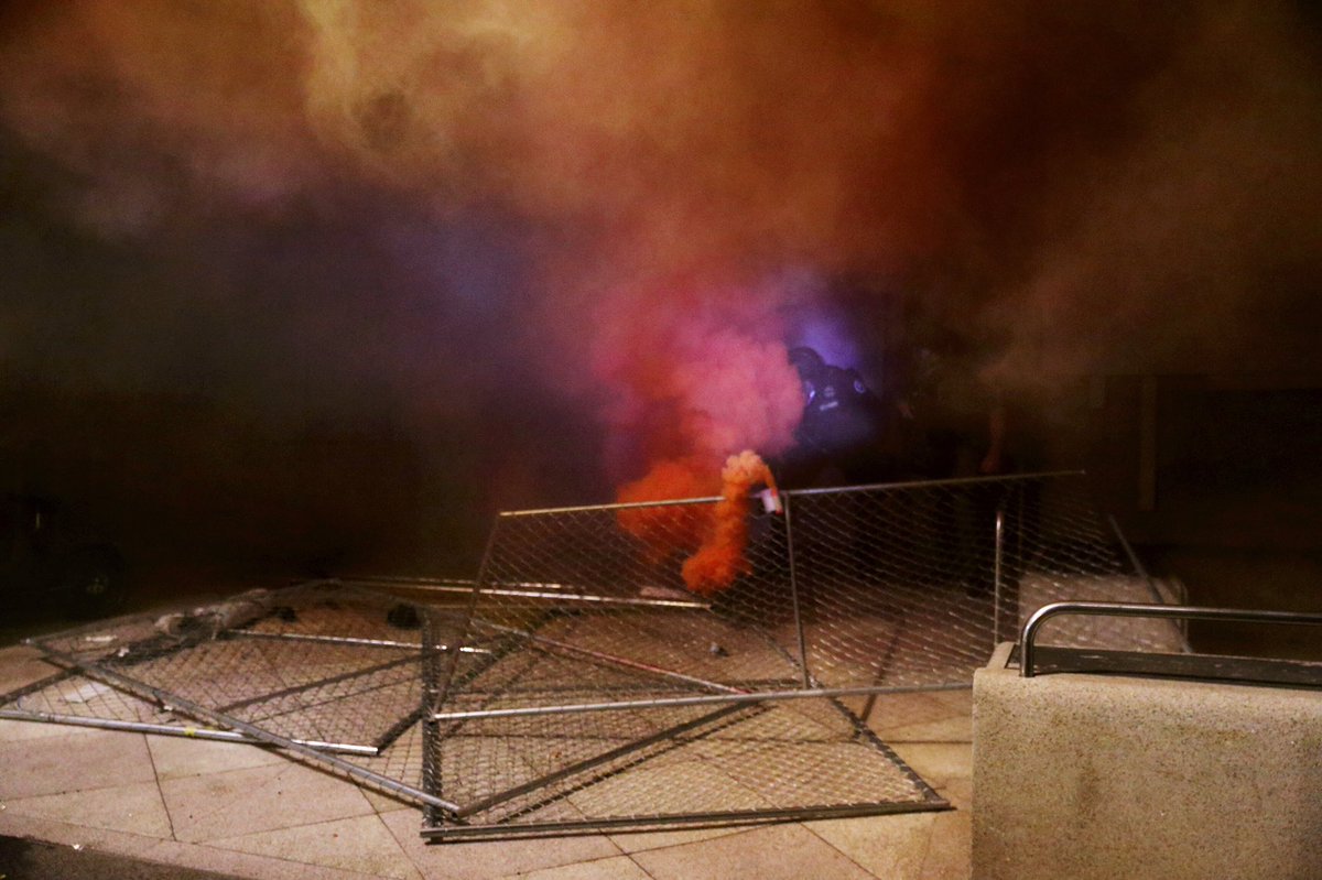 Protesters have now used fencing to barricade doors at the JC and the Edith Green Federal Building. Police briefly came out of the JC and fired munitions from a cutout in the plywood. Protesters have used a few more smoke bombs. LRAD announcements to not block doors, disperse