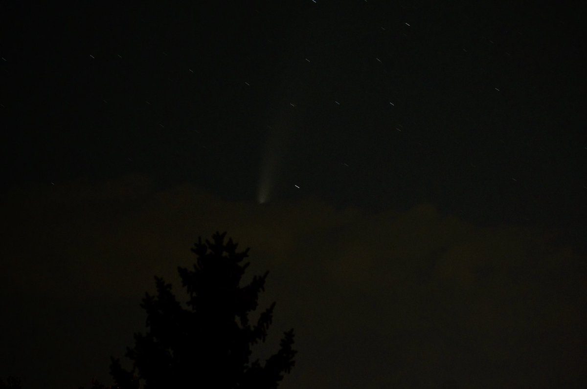 DocWX's tweet photo. That’s not a bat signal. That’s Comet Neowise behind a cloud. 

#cometNEOWISE #NEOWISE #cowx #Astrophotography https://t.co/ghOQNDaneB