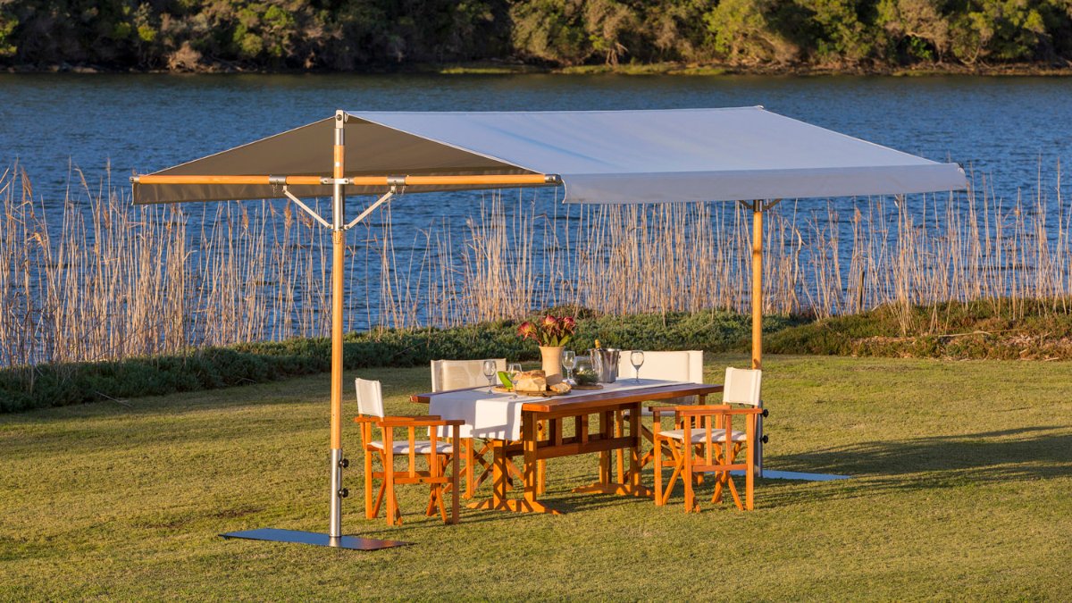 Enjoy outdoors beneath a Pappilon Shade Pavilion from Woodline. This modern shade is great for large dining &amp; lounge areas on your deck or patio. It's available in eucalyptus or stainless steel with multiple Sunbrella fabrics. decorinteriorsus.com/woodline-papil… #woodline #papillon #shade