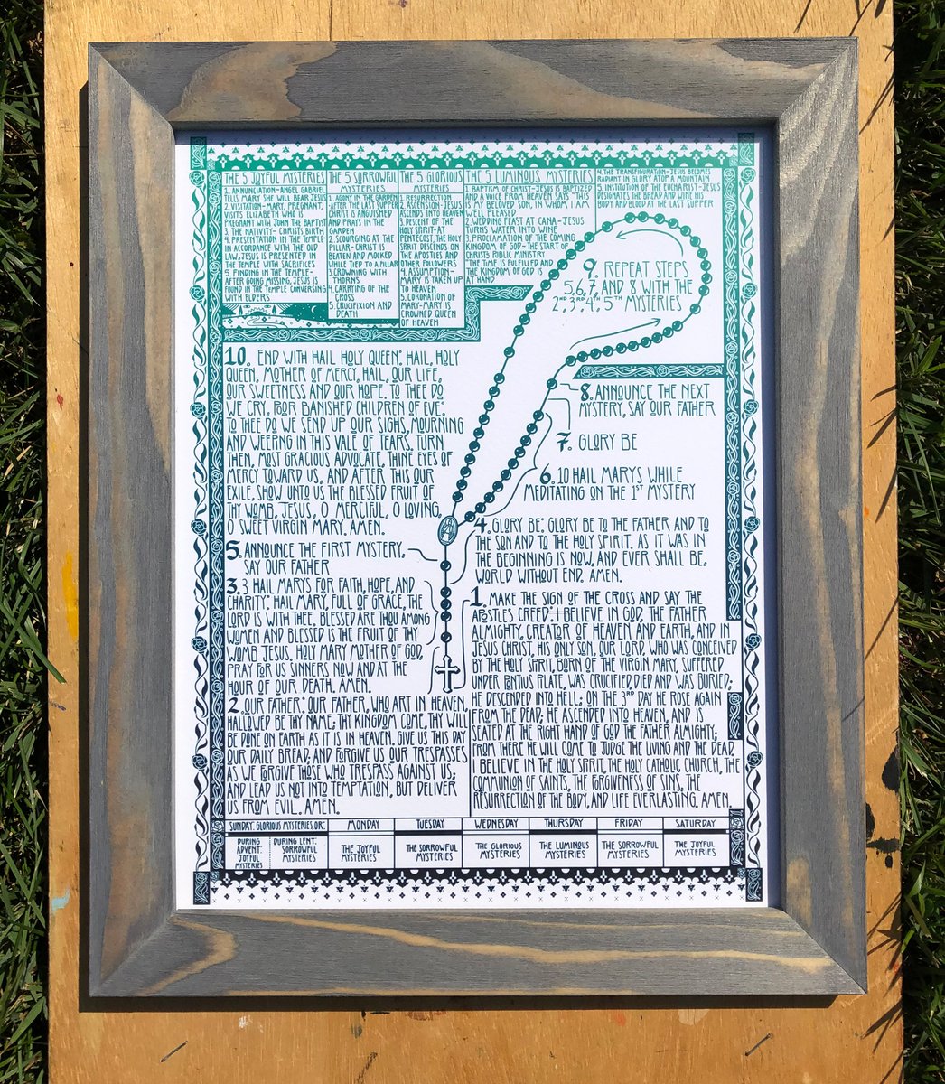 next up i got the 4TH PRINTING of the rosary print going down, right here. new color for the 4th printing. i call this the garden color scheme, its like deep green and blue of nature, the cool grey frame is like grey stone, + the warm wood in the frame is like wood (it is wood)