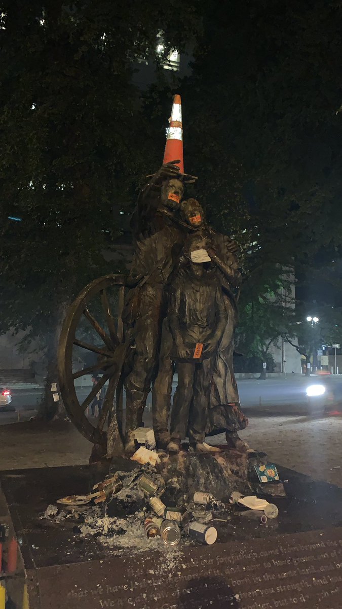 Tonight, the colonizer statue features the remains of a tiny trash fire, plus some tape that says “land back” over the people’s mouths.