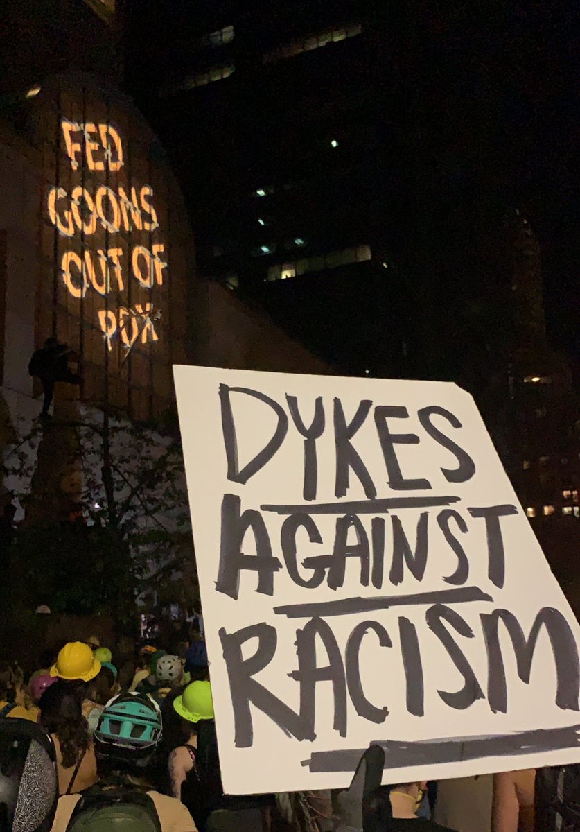 The words “FED HOONS OUT OF PDX” are being projected onto the front of the Justice Center.