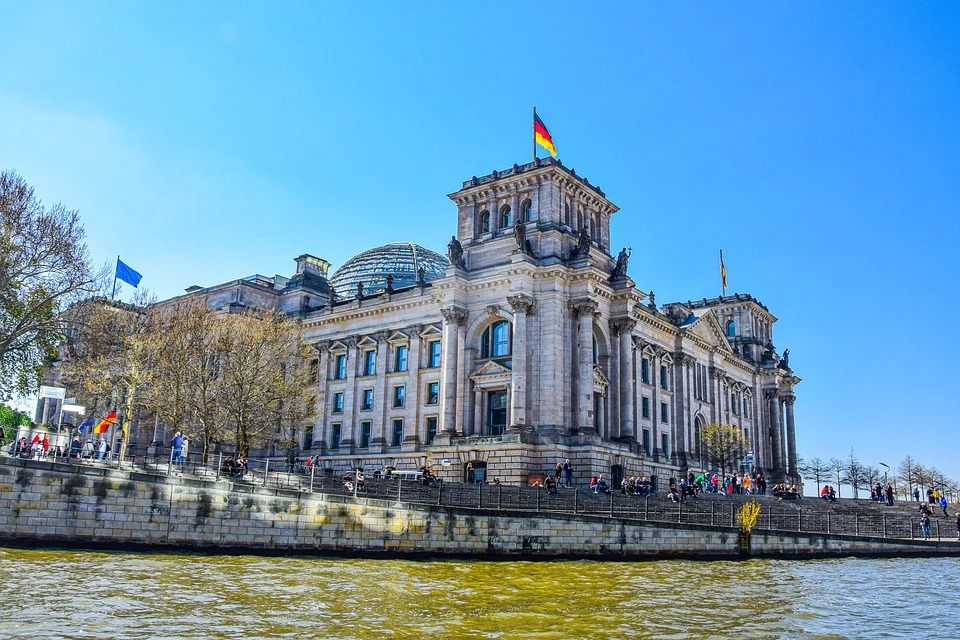 Gebäude des Deutschen Bundestages unter strahlend blauem Himmel von der Spree aus gesehen