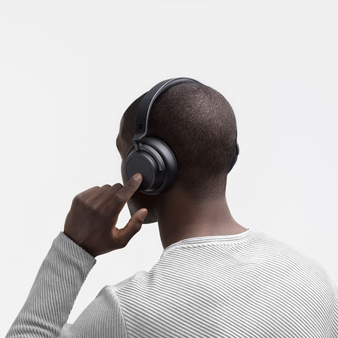 A man taps his Surface Headphones 2 with his finger.