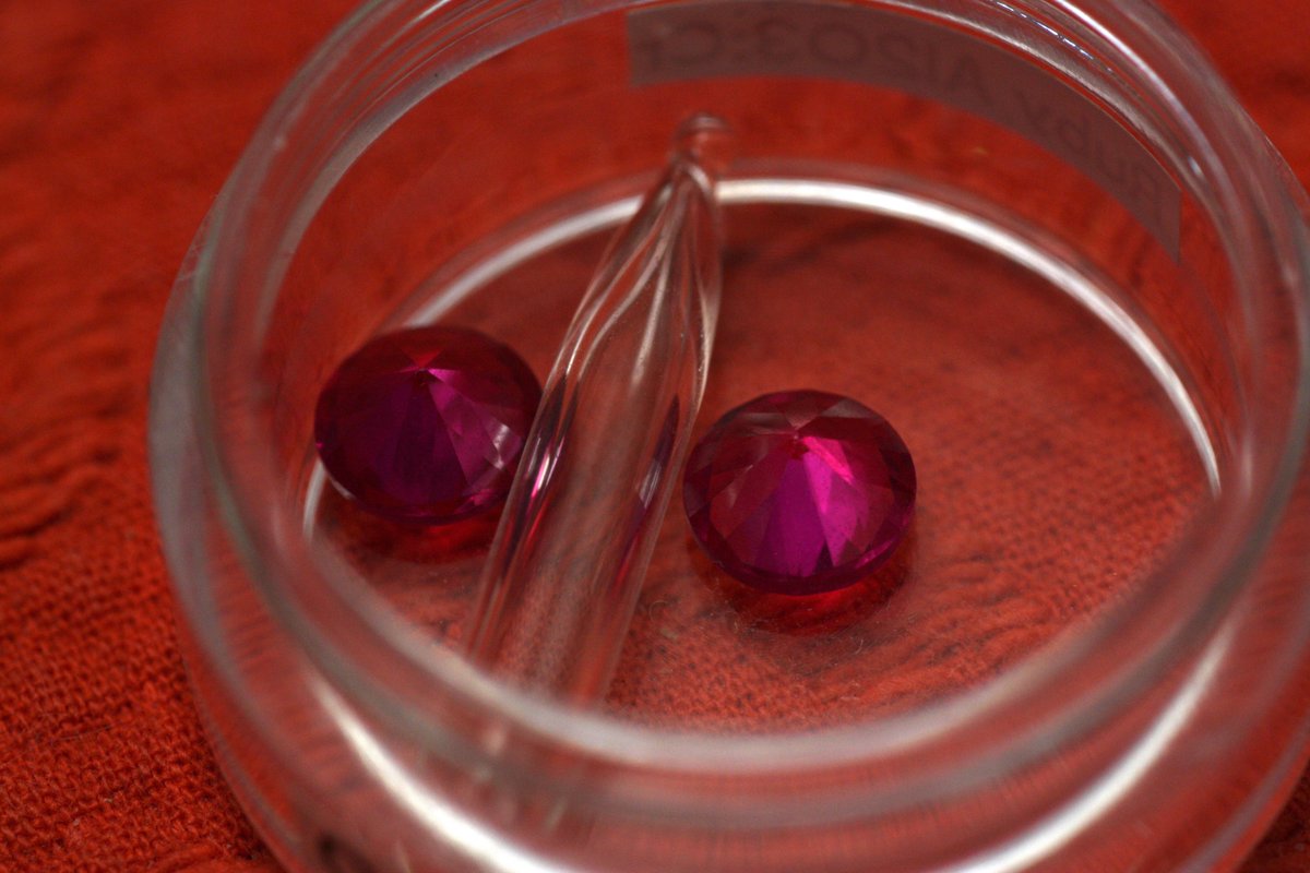 Oxygen  @elementphotos. Discharge tube's quite difficult to get a good photo of - glow is quite faint and diffuse white, though purple at the source to the eye. The container has a smaller gas ampoule plus two synthetic rubies (Al2O3 with Cr impurities giving the colour).