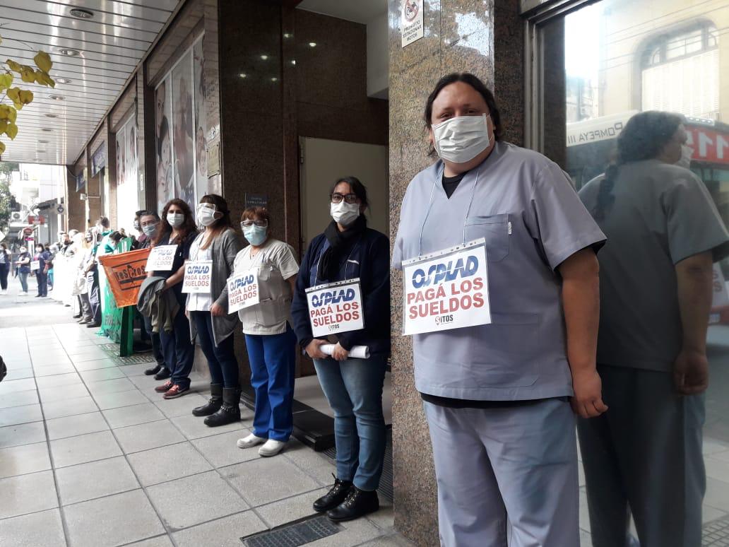 #Ahora | Abrazo al Policlínico del Docente | Bassignani, Sec Gral del SiTOSPLAD: "Aún no cobramos la totalidad del sueldo de junio, no tuvimos aumentos en el transcurso del año y con la pandemia se agudizan estos problemas. Reclamamos al @MinTrabajoAR  una pronta intervención.