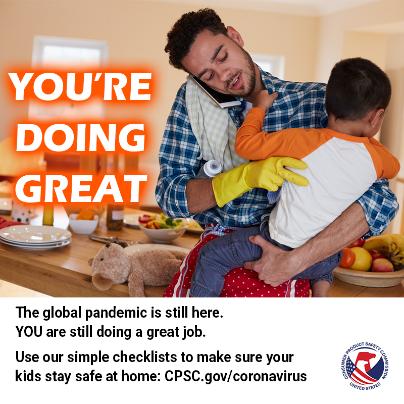 A dad holding a kid while talking on the phone wearing dish gloves. The text reads: You're doing great. The pandemic is still here. You are still doing a great job.