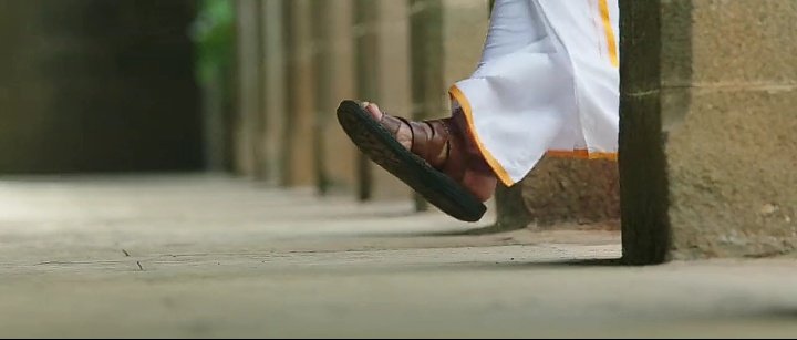 Foot part is covered and the man is holding his vesti on his left hand and having brown soled wrist watch 