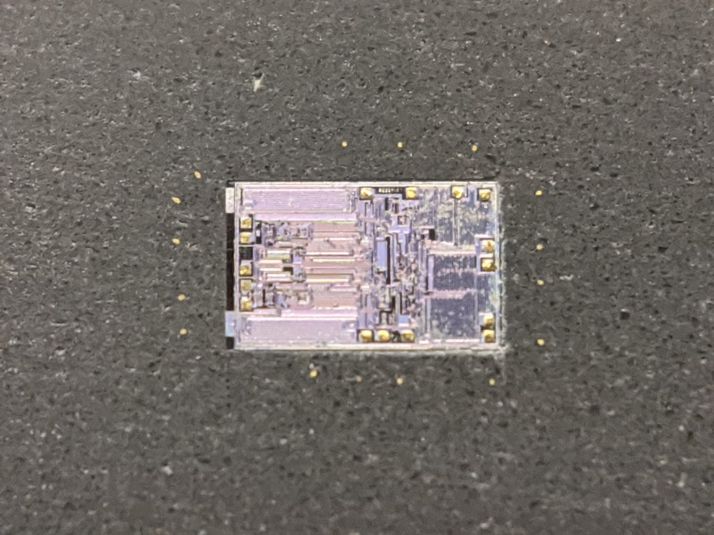 zooming in on the silicon chip, see those little gold dots around the outside? those are the ends of the bond wires. they attach to the metal lead frame which you can't see from this angle. then they arc up and over onto the chip. you can see the gold dots there too.