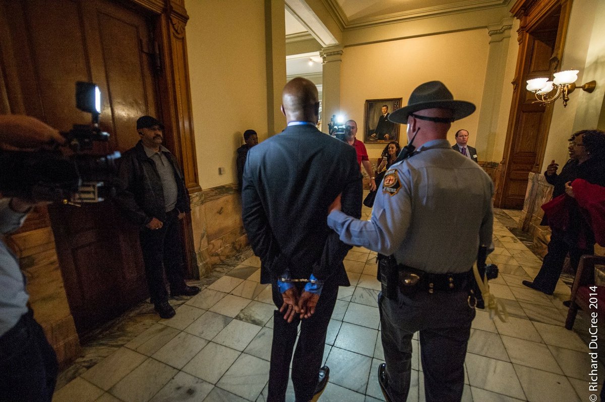 ReverendWarnock's tweet photo. Not a lot of candidates share photos of them in handcuffs, but I’m proud of this one. 

I led a sit-in at the GA Capitol for Medicaid expansion because I believe health care is a human right. 

Next time I'm escorted by Capitol Police, it will be to my new office as U.S. Senator. https://t.co/1fq3OmcUk0