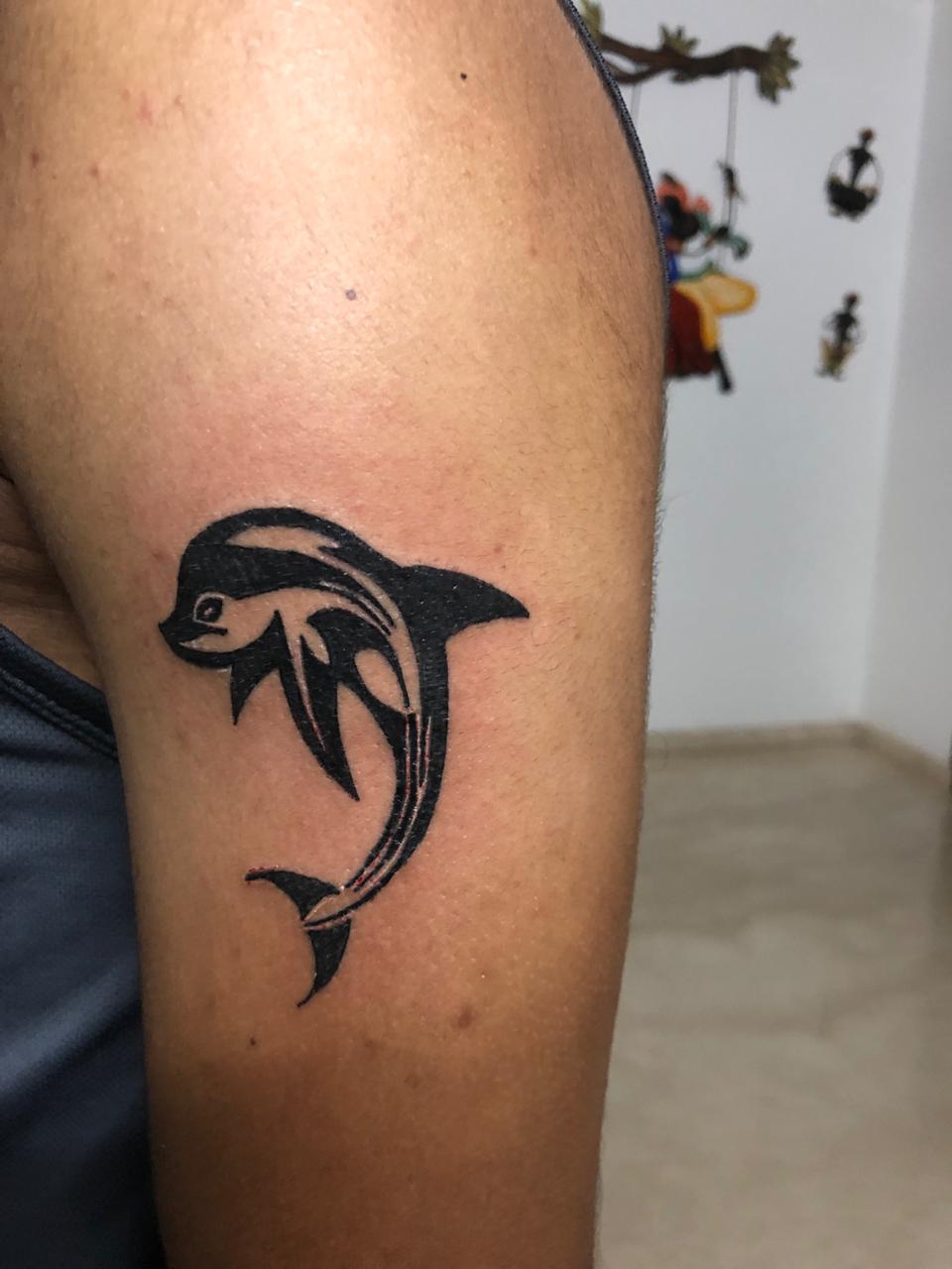 Micro-realistic dolphin tattoo on the ankle.