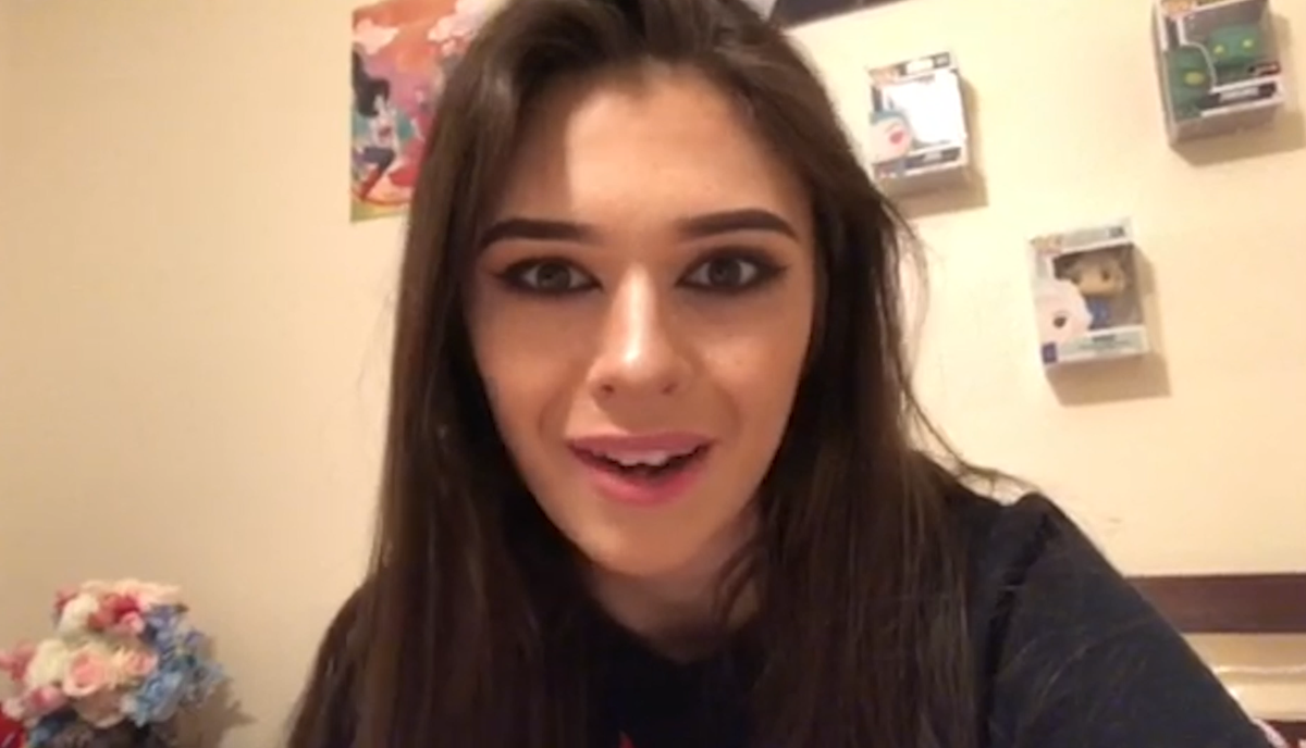 Nicole Maines sitting at home sharing her story in front of some popco gear!