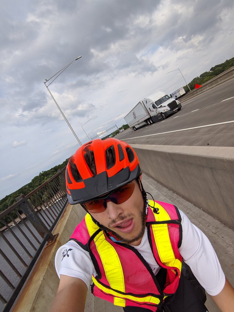 Selfie of Ian riding his bike on the bike trail, with a semi truck visible on the interstate alongside it.