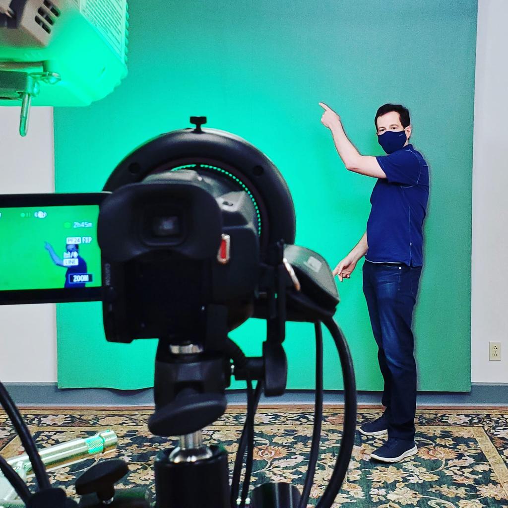 Instructor being video recorded in front of green screen.