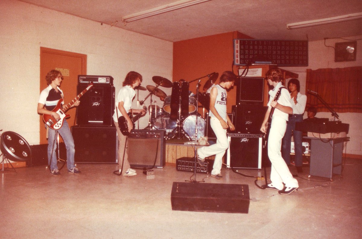 JasonAtkinsonLA's tweet image. #FlashbackFriday - circa #1981, #WinslowAZ, my first summer rock #band - Fugitive - at a #VFW gig with the #bingo sign above!! That’s me decked out all in white, looking back at my @Peavey #Classic #410 #guitar #amp and @mxrpedals #distortionplus and a black @CarvinGuitars #CM140