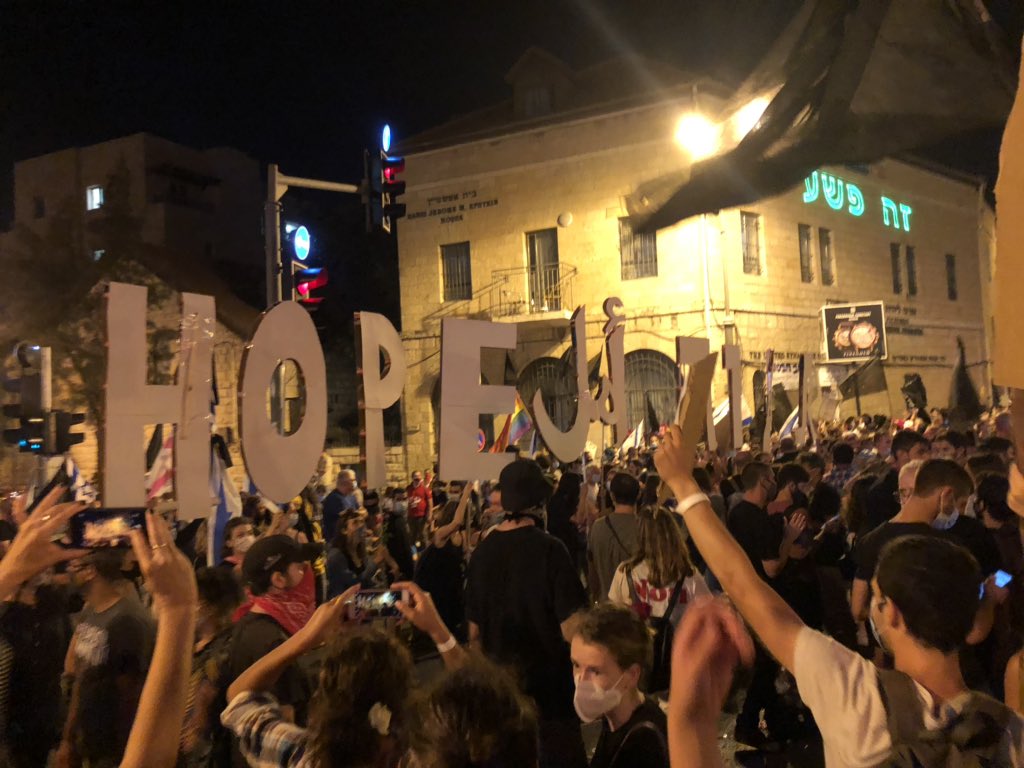 Protestors hold up letters spelling out “hope” in English, Hebrew, Arabic