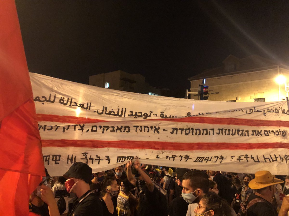 Sign in Arabic, Hebrew, Amharic: “breaking institutionalised racism - unity of the struggles, justice for all”
