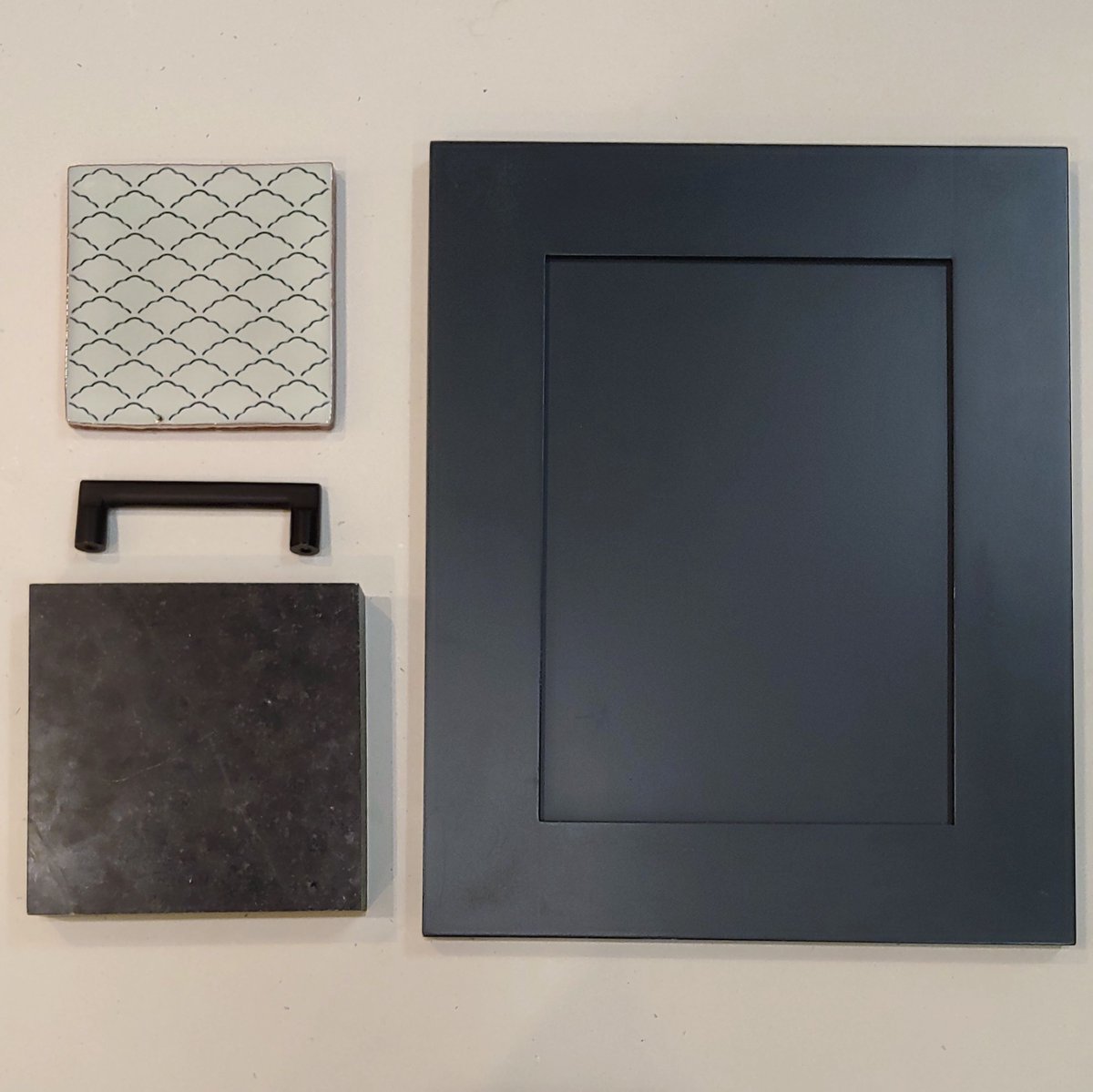 Kitchen project with dark blue cabinets, soapstone countertops, handcrafted tile backsplash, and matte black hardware. We created a flat lay to show the different materials used up close - we didn't have a sample of the exact hardware used in this kitchen so we had to improvise!
