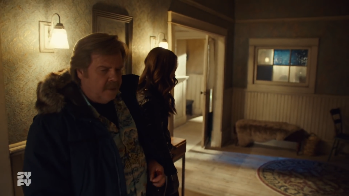 When Nedley says "Well..." & the camera now conceals the living room doorway, that could have been Varun's cue to come out. He would know he would be concealed behind the camera & and would be able to move fluidly with the camera to get in place.