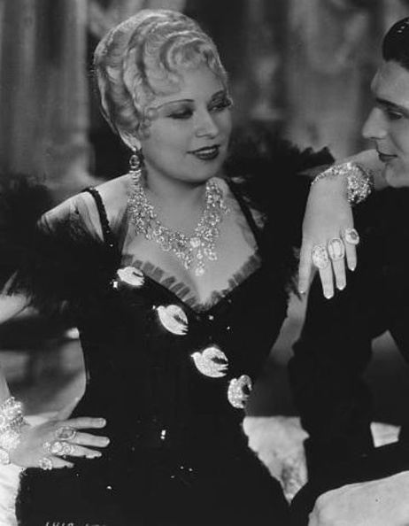 Edith’s flock of birds gown with a picture hat is the most beautiful in the picture. Mae’s skin glows like marble. Mae asked for an eye-catching gown for a scene where she didn’t have a lot of dialogue to keep audience riveted on her. The birds were outlined with brilliants.