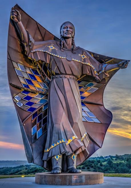 LeDWalk's tweet photo. Just learned about this today. She’s a beauty! Dignity is a 50ft sculpture in South Dakota by artist Dale Claude Lamphere & depicts an Indigenous woman in Plains-style dress receiving a star quilt. #DignityStatue https://t.co/EiTAvVJOAn https://t.co/ya9e9LPPIK
