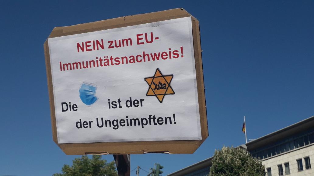 "The mask is the Nazi Jewish star of the unvaccinated", this poster reads.   #b0108