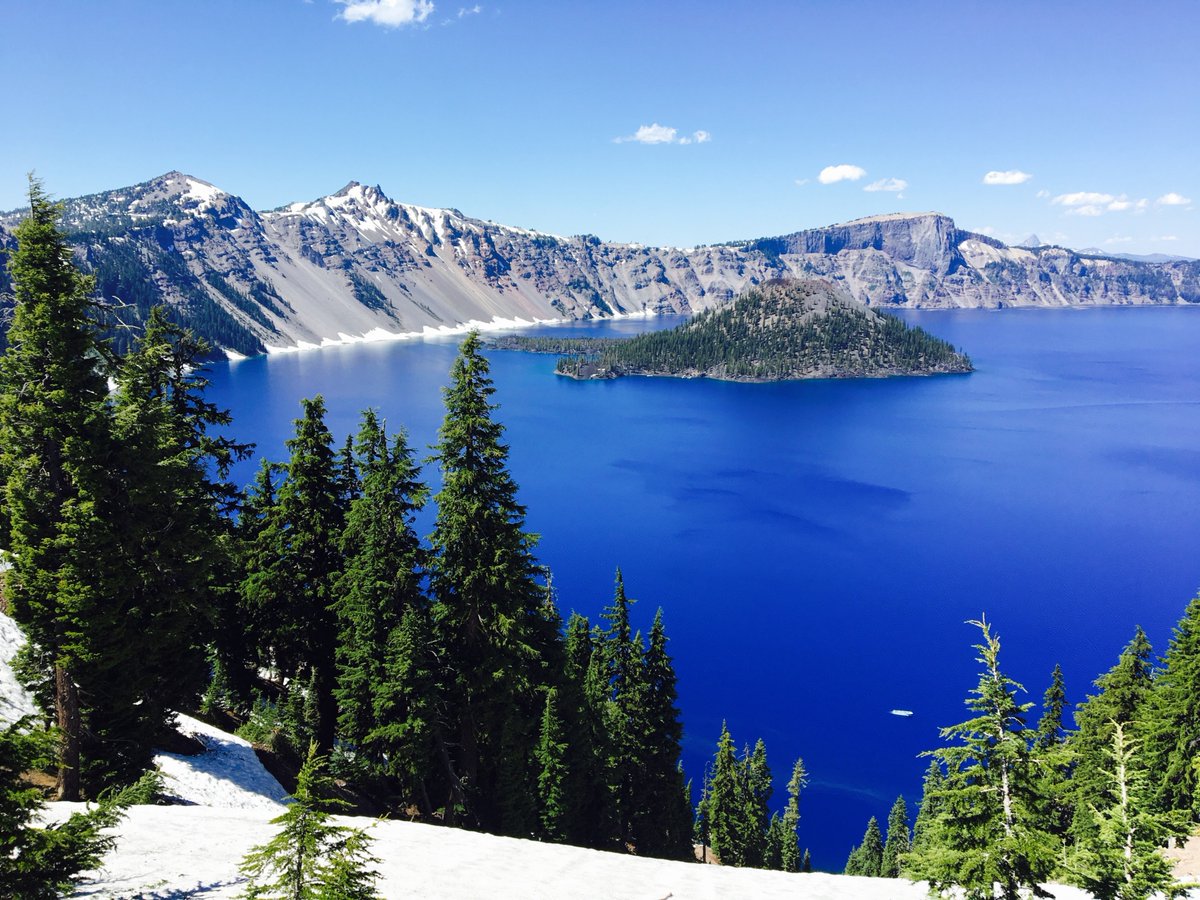bright blue lake with wizard island in the middle and the rim on the background
