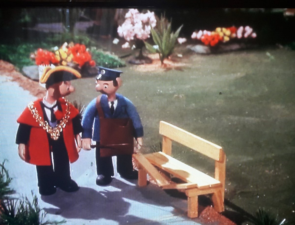 Trumpton Town Park is what should be an award-winning example of municipal planning. Tidy, orderly and well equipped, and we get to see a lot of it. Here's The Mayor and Mr Craddock picking up litter and inspecting a broken bench. Bin and flowers both superb attention to detail.