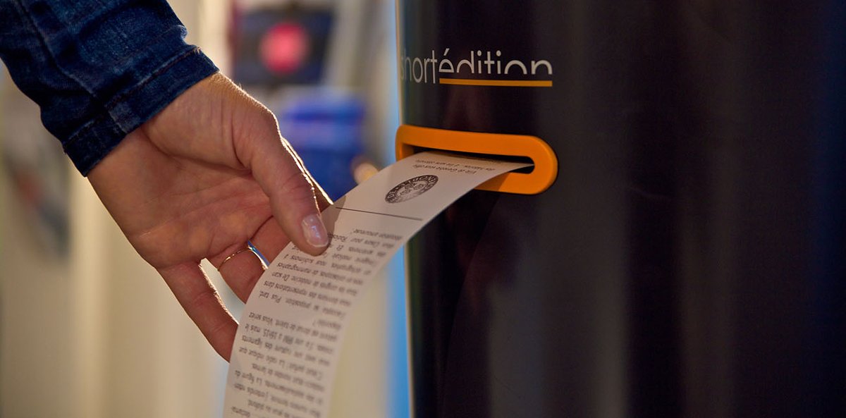 hand taking a short story print out sheet from the machine