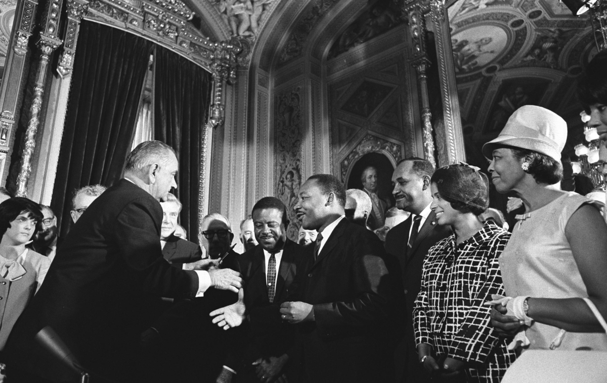 A photo of President Johnson after signing the Voting Rights Act of 1965. He is about to shake hands with Dr. Martin Luther King, Jr.