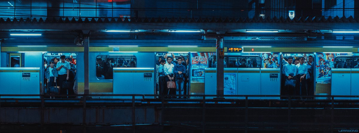 Photography by Liam Wong of Tokyo at night. A train station platform captured four times. This image is of three men in three doorways of a crowded train waiting for the doors to close.