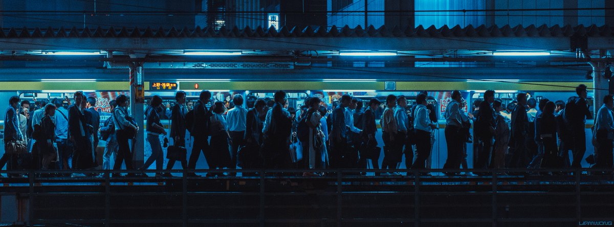 Photography by Liam Wong of Tokyo at night. A train station platform captured four times. This image is of a crowd exiting the train.