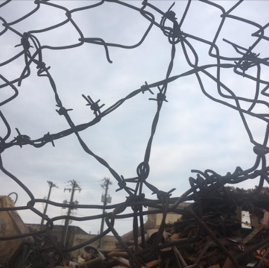 Repairing a chainlink fence with a bit of barbed wire.