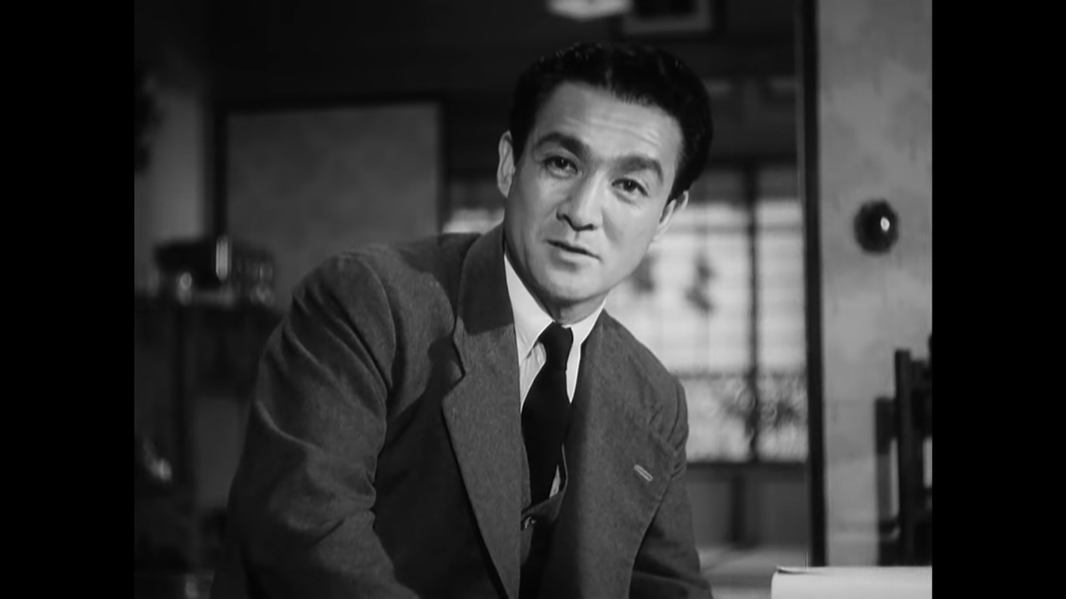 Here’s a direct look at the camera in conversation. The previous medium shot of Shôichi, which was from the front as he turned to speak to Noriko, expanded the sphere of conversation; here, Ozu moves back to a 1-on-1 dialogue.