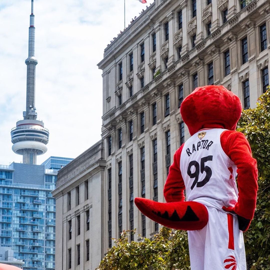 The Toronto Raptors mascot looking towards the CN Tower and surrounding buildings 