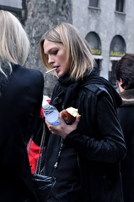 vladasdoll's tweet image. sasha pivovarova eating an apple while smoking a cigarette, leaving d&amp;amp;g show @ mfw