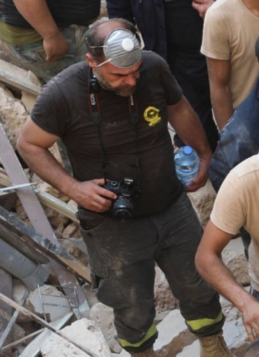 This T-shirt logo is Lebanese Civil Defense.Controlled by Hezbollah.And he's there to TAKE PHOTOS?!