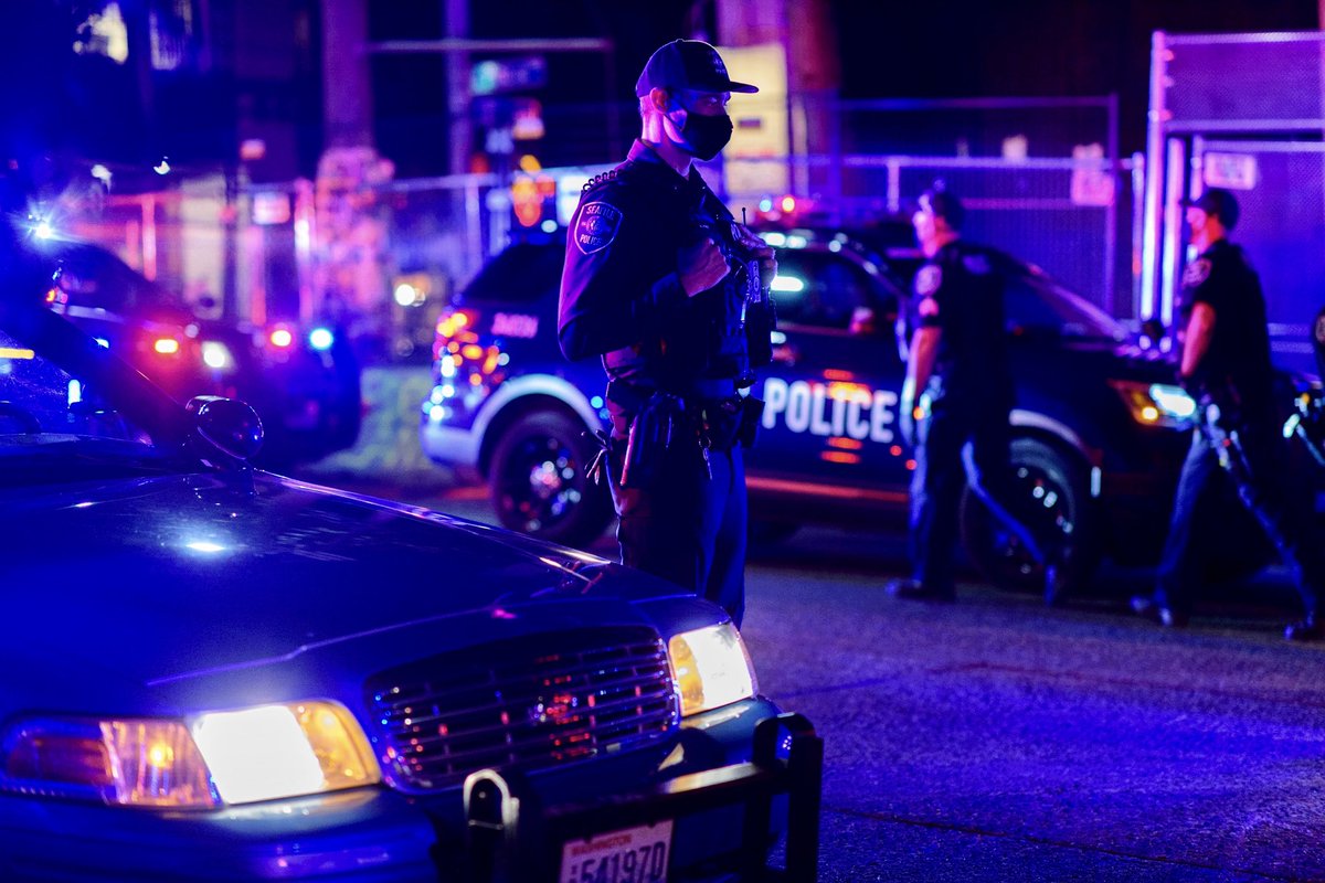 Couple scenes from  #seattleprotests last night at the East Precinct. After a small group of protestors blocked the side entrance to the station, SPD responded with a large force of cars with lights & sirens. SPD retreated after protestors approached them slowly with raised hands.