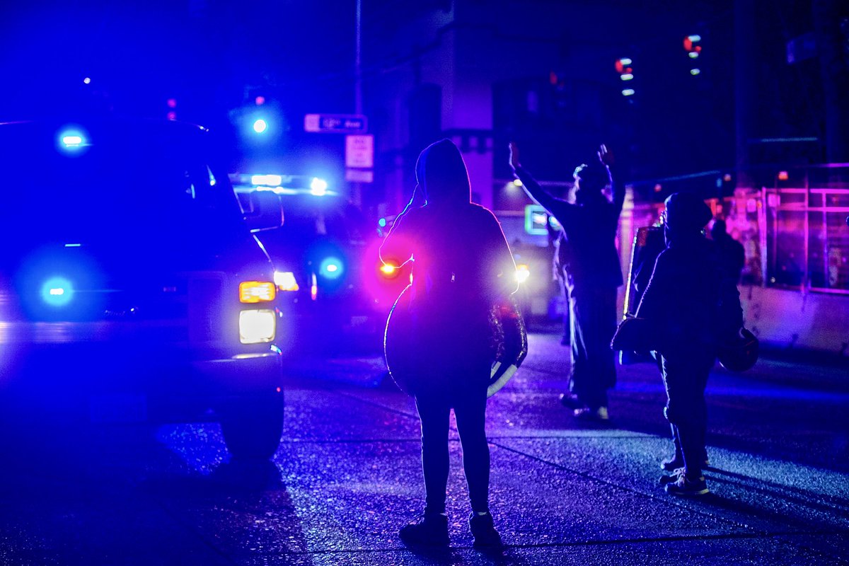Couple scenes from  #seattleprotests last night at the East Precinct. After a small group of protestors blocked the side entrance to the station, SPD responded with a large force of cars with lights & sirens. SPD retreated after protestors approached them slowly with raised hands.