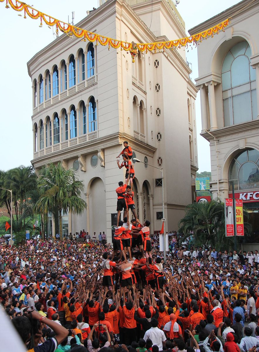 to community festivals which culminate in the breaking of a clay pot with yogurt (called a Dahi Hundi) hung WAY up high through the use of a human pyramid!